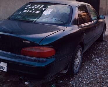 əllə çəkilmiş maşın şəkilləri: Kia Sephia sedan - Kuzov: 4 qapılı sedan, tünd yaşıl rəng - Ön hissə — 4