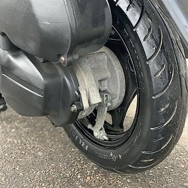 18 disk təkər: Gümüşü rəngdə, qara detallarla bəzədilmiş Suzuki skuter. Bu model — 4