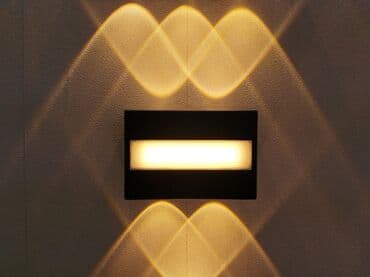 Qara rəngli, düzbucaqlı formalı divar lampası. Otağa yumşaq, xoş bir