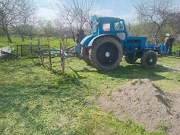 Mavi rəngli təkərli traktor, arxaya qoşulan ot yığan/çırpıcı (saman-ot