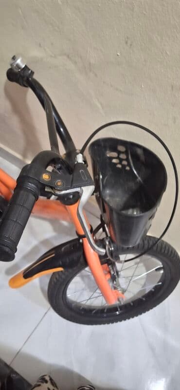 Bu, narıncı rəngli uşaq velosipedidir. Ön tərəfində əşyaları daşımaq