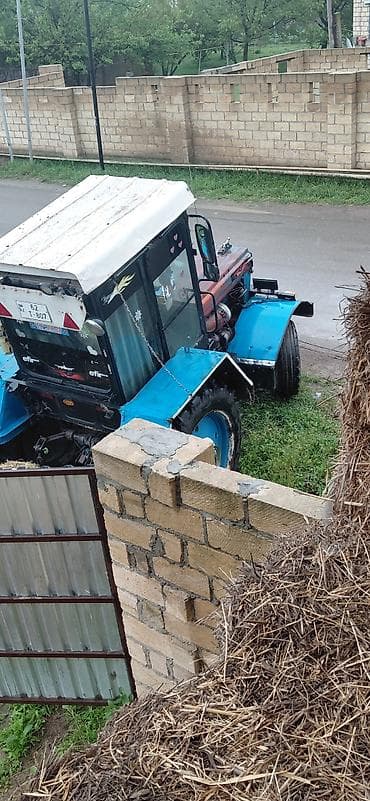 Traktor – kabinəli, mavi rəng çalarlarında. Güclü arxa təkərli, ön dar