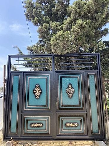 Qara rəngdə, bürünc elementlərlə bəzədilmiş metal qapı. Qapının