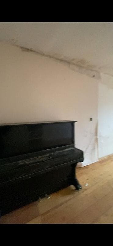 Düz divar qarşısında yerləşən klassik, şaquli (upright) pianino