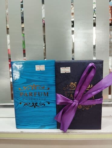 Hər biri zərif lentlərlə bəzədilmiş iki ətir qutusu. Bir qutu mavi