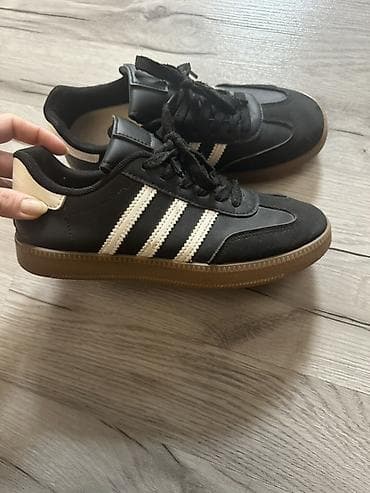 Kişi ayaqqabıları: Qara rəngli idman ayaqqabısı, üç ağ zolaqlı klassik dizayn. Üst hissə — 3