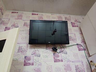 lg azerbaijan: Divara quraşdırılmış qara rəngli LG LCD televizor. Televizorun altında — 2