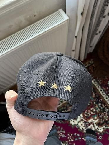 dini geyim: Snapback papaq – qara rəngdə, düz vizorlu model. Ön hissədə qızılı — 2