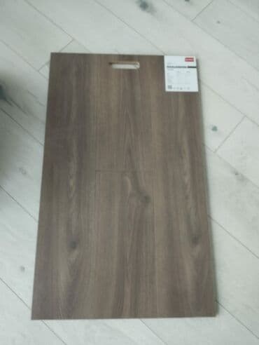 döşəmə taxtaları: Boz-qəhvəyi rəngdə, taxta görünüşlü laminat döşəmə nümunəsi. Səthində — 2