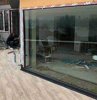 Böyük şüşə panelləri və möhkəm alüminium çərçivəsi olan sürüşmə qapı