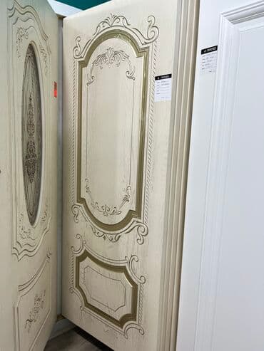 Bej rəngdə, oyma naxışlı qapı. Klassik üslubda dizayn edilmişdir. Ev