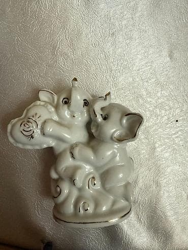 Ağ rəngdə, zərif fil fiqurları. Bu dekorativ əşya, bir-birinə sarılmış