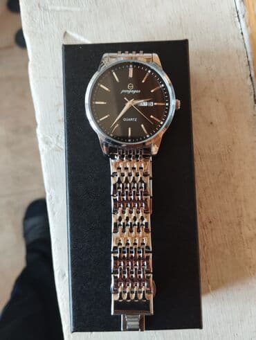 бу вещи: Gümüşü rəngdə metal kəmərli, qara siferblatlı saat. Siferblatda — 1