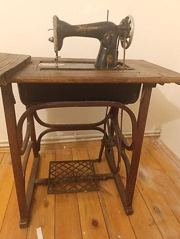qedimi pullar: Ayaq pedalı ilə işləyən köhnə tip tikiş maşını və taxta stolüstü — 2