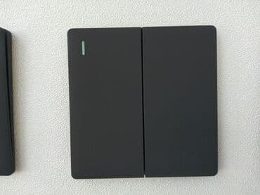 Qara rəngdə olan ikiqat elektrik açarı. Divara quraşdırılıb və müasir