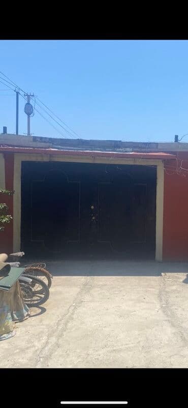 Metal darvaza, qara rəngdə, avtomobilin keçməsi üçün nəzərdə tutulmuş