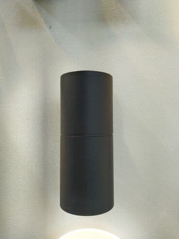Qara rəngdə silindrik formalı divar lampası. Yığcam dizaynı onu