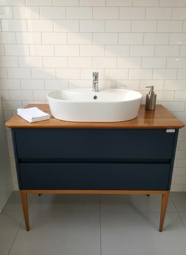 Oval formada ağ rəngli keramika lavabosu olan tünd boz rəngli taxta