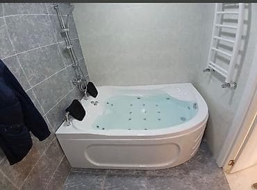 Ağ rəngli künc jakuzi vannası, rahatlıq üçün iki qara baş dayanağı ilə