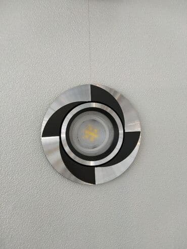 Gümüşü rəngdə, dairəvi formalı, qara elementləri olan, divara