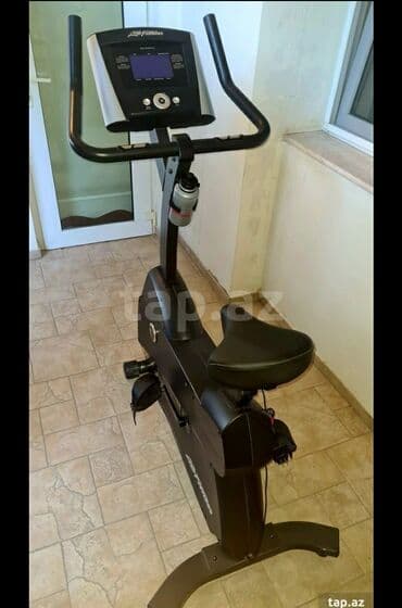 gül qabı: Life Fitness markalı, qara rəngdə, stasionar velosiped. Üzərində — 1