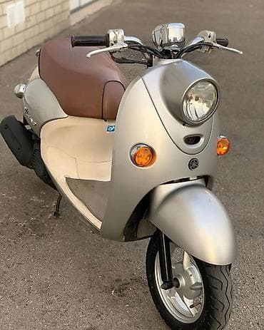 elektrikli ot bicen: Yamaha markalı, retro tərzdə gümüşü və bej rəngli skuter. Bu skuter — 2
