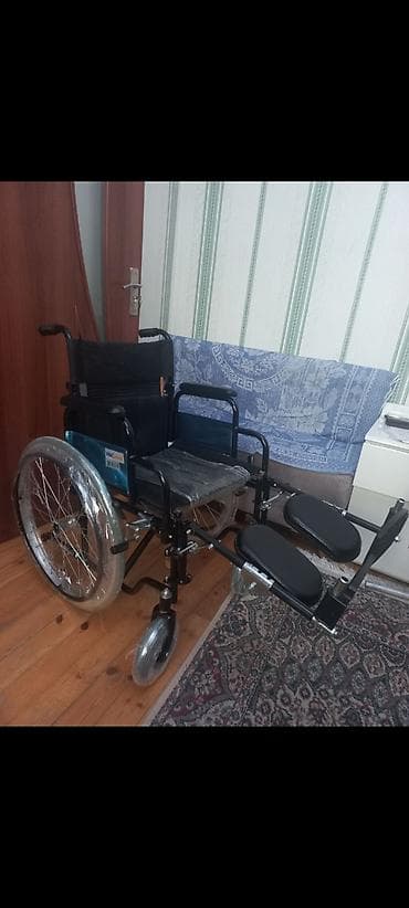 Qara rəngdə, ayaq dayaqları olan əlil arabası. Böyük təkərləri və