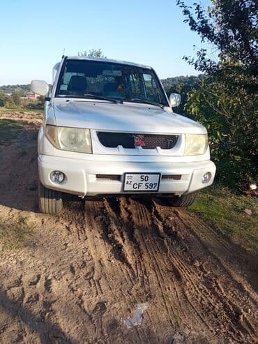 турбо аз трактор: Ağ rəngli, 4 qapılı Mitsubishi Pajero SUV. Avtomobilin arxa hissəsində — 2