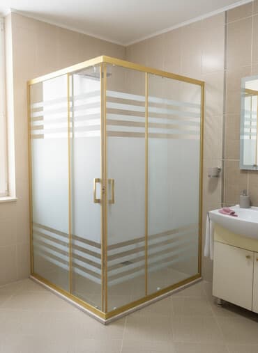 Qızılı rəngli çərçivəyə malik, şüşəli sürüşən duş kabinəsi. Üfüqi