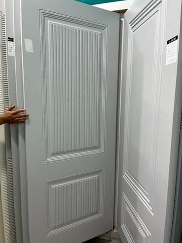 Ağ rəngdə, klassik üslubda hazırlanmış qapı. Qapının üzərində şaquli