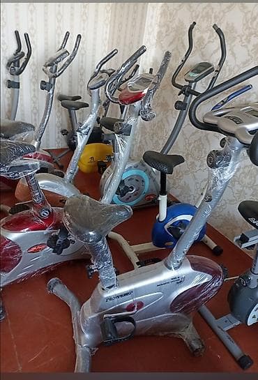 Müxtəlif rənglərdə və dizaynlarda olan stasionar velosipedlər. Bu — 1