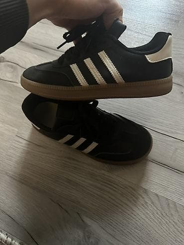 Kişi ayaqqabıları: Qara rəngli idman ayaqqabısı, üç ağ zolaqlı klassik dizayn. Üst hissə — 2