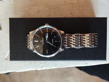 бу вещи: Gümüşü rəngdə metal kəmərli, qara siferblatlı saat. Siferblatda — 2